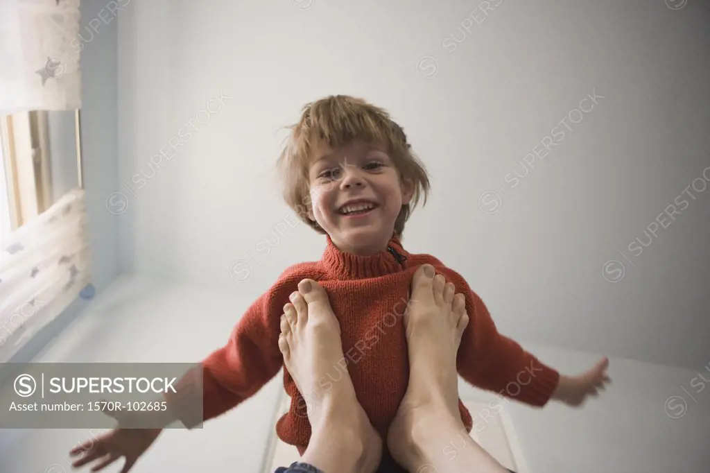 Young boy balancing on adult feet