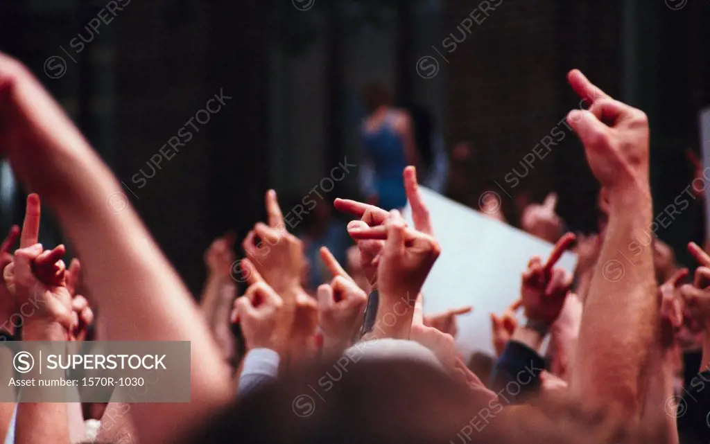 arms raised in a crowd giving the finger in protest
