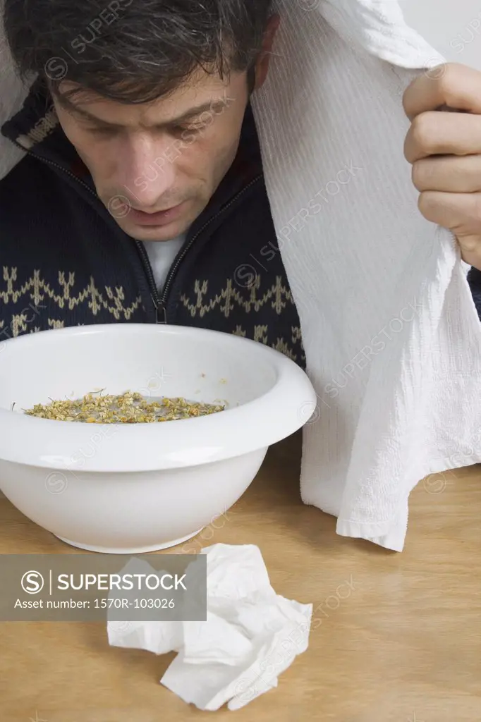 A man with a cold breathing steam from a bowl