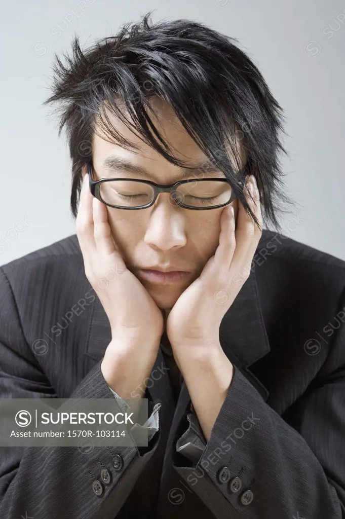 An Asian businessman resting his head in his hands