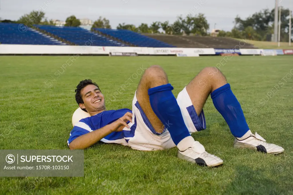 A soccer player resting on a soccer ball