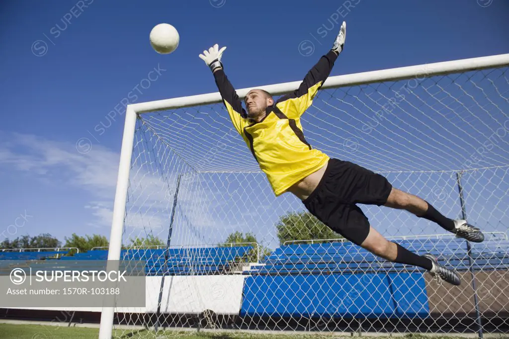 A soccer goalkeeper diving to block a shot
