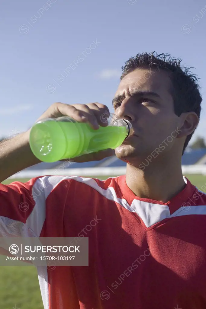A soccer player drinking a sports drink