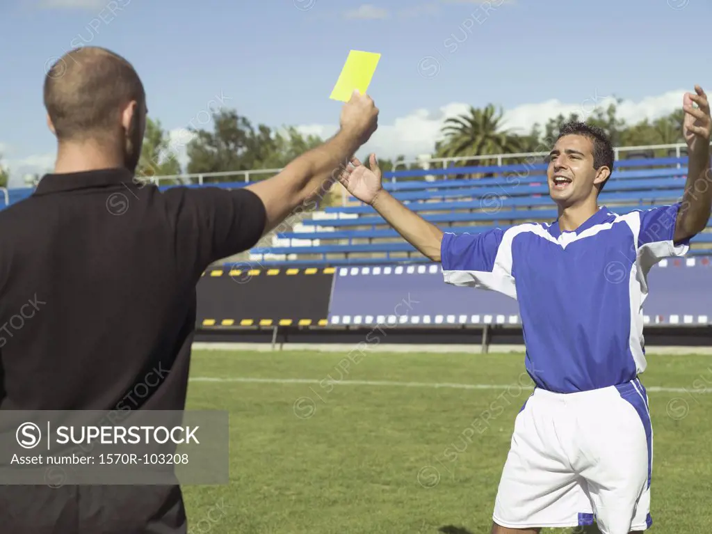 A referee giving a soccer player a yellow card