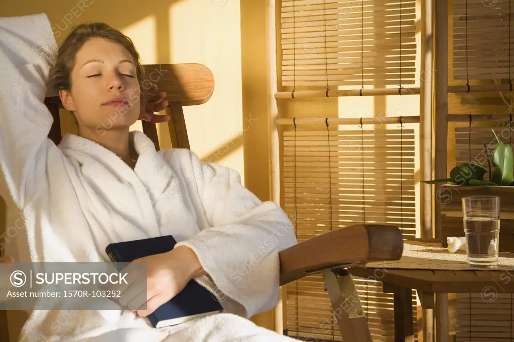 Woman sitting in chair with eyes closed wearing bathrobe