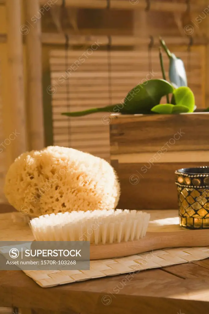 Bath sponge, brush and candle on table