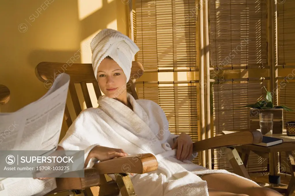 Young woman in bathrobe reclining in wooden chair