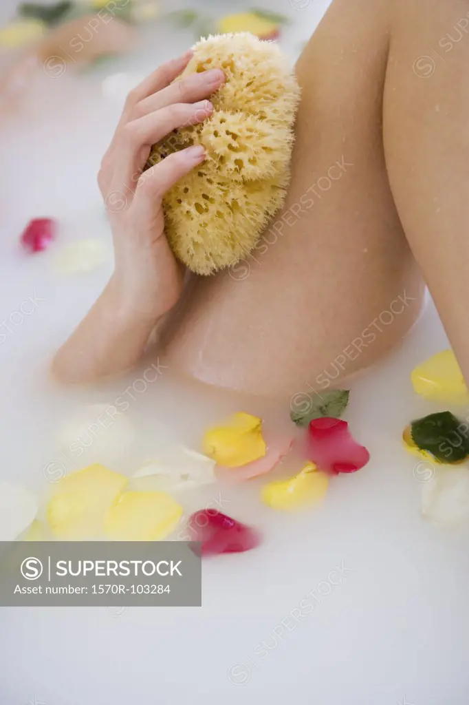 Close-up of young woman holding sponge in bathtub