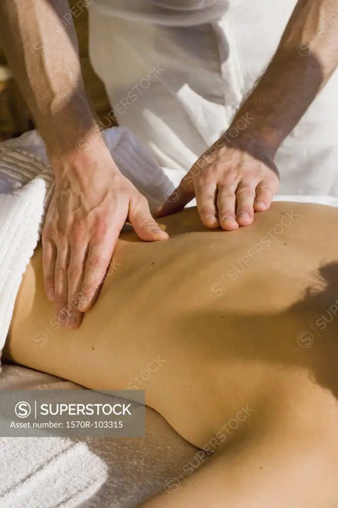 Young woman lying on front receiving back massage
