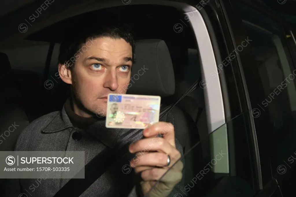 Man sitting in car and holding his ID card