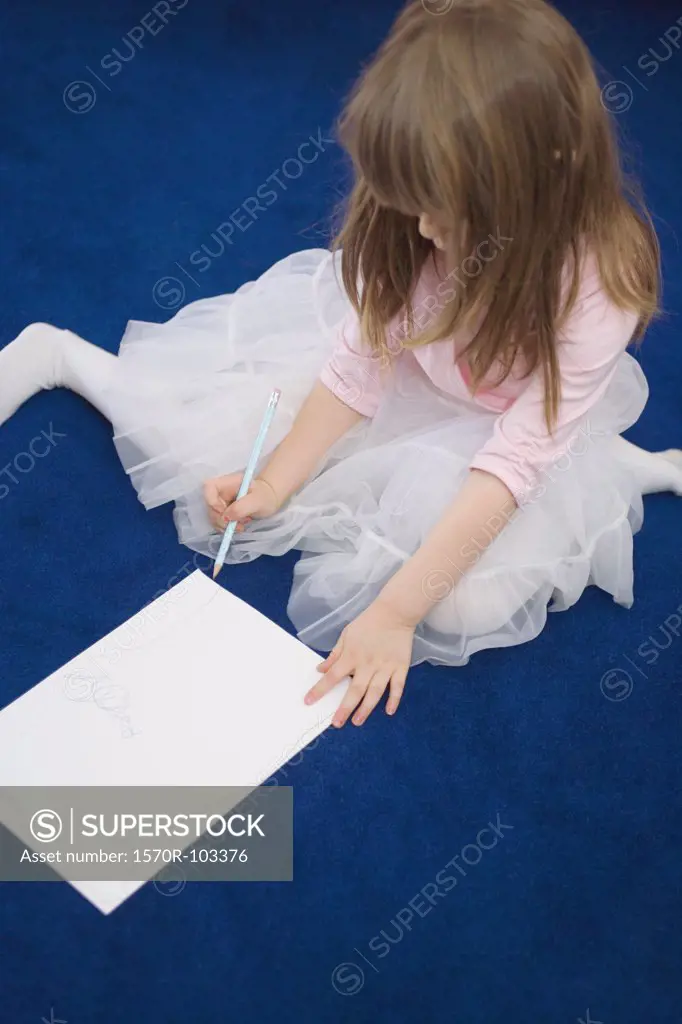 Young girl sitting on floor drawing