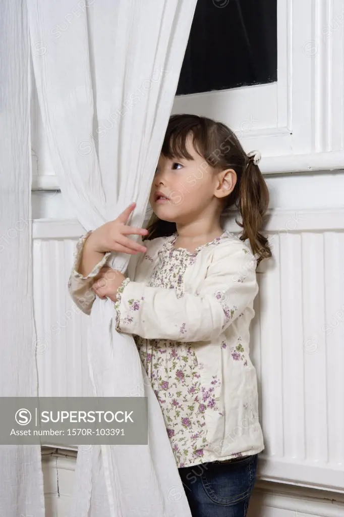 Young girl holding a curtain