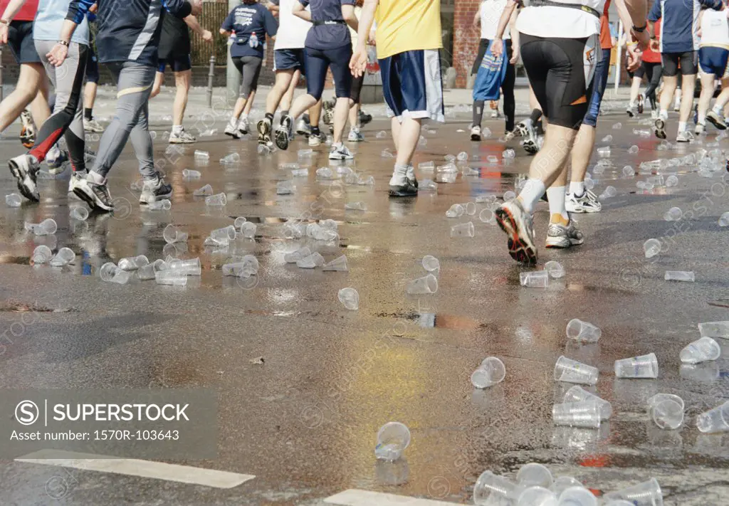 Plastic cups scattered over road beneath marathon runners