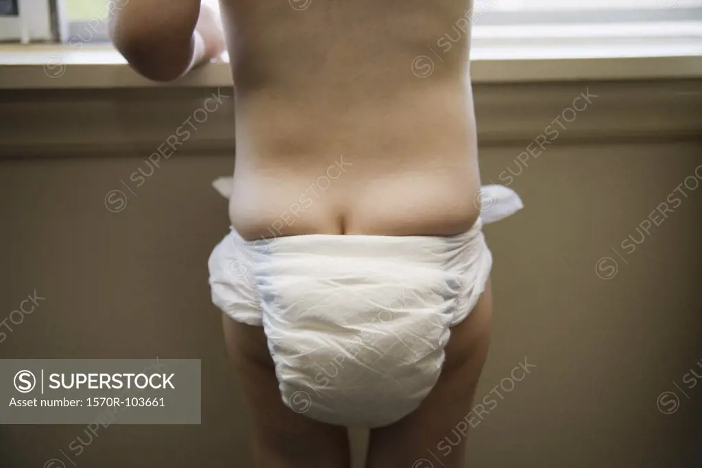 Toddler wearing diaper and looking out window