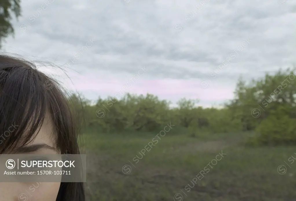 Young woman standing in field with dramatic sky above