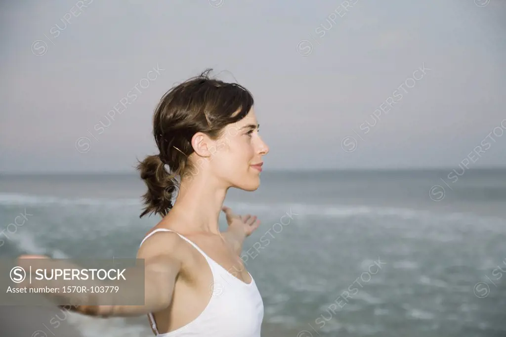 Woman standing on beach with arms outstretched