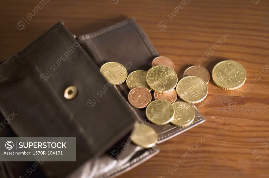 Open wallet with coins spilling onto table