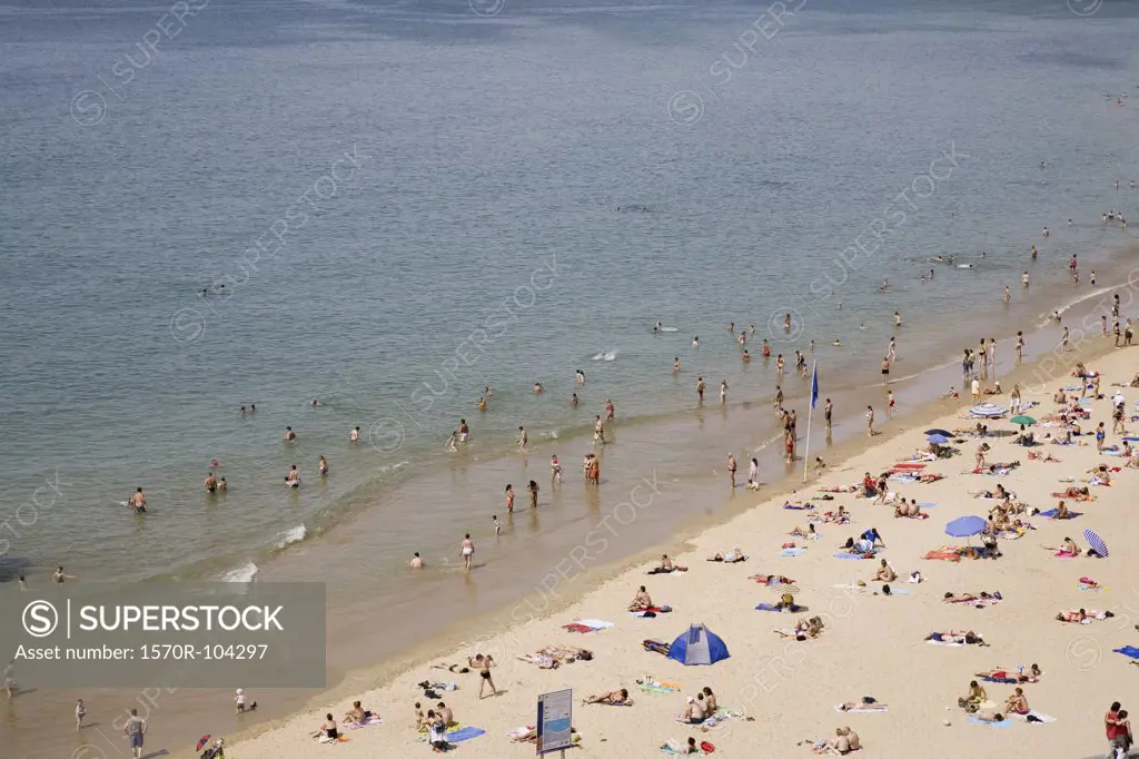 People swimming in sea and sunbathing on beach