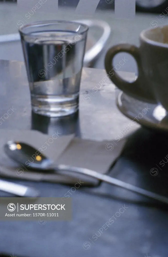 coffee cup, spoon and glass of water on a table