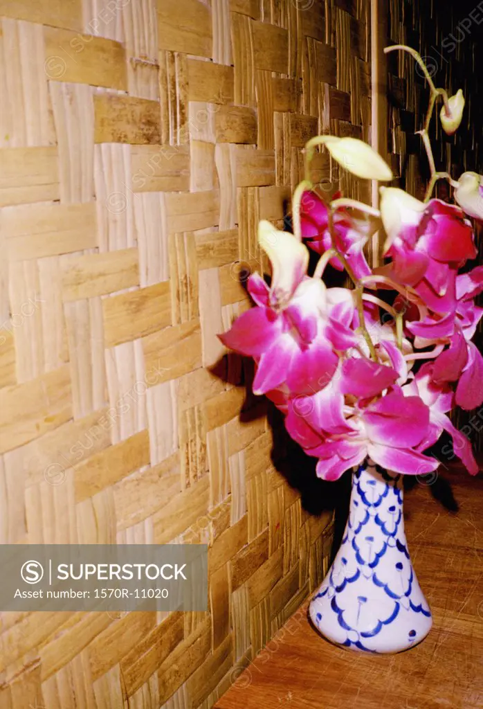 vase of pink flowers next to a wooden wall