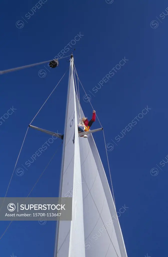 Woman perched on mast of yacht