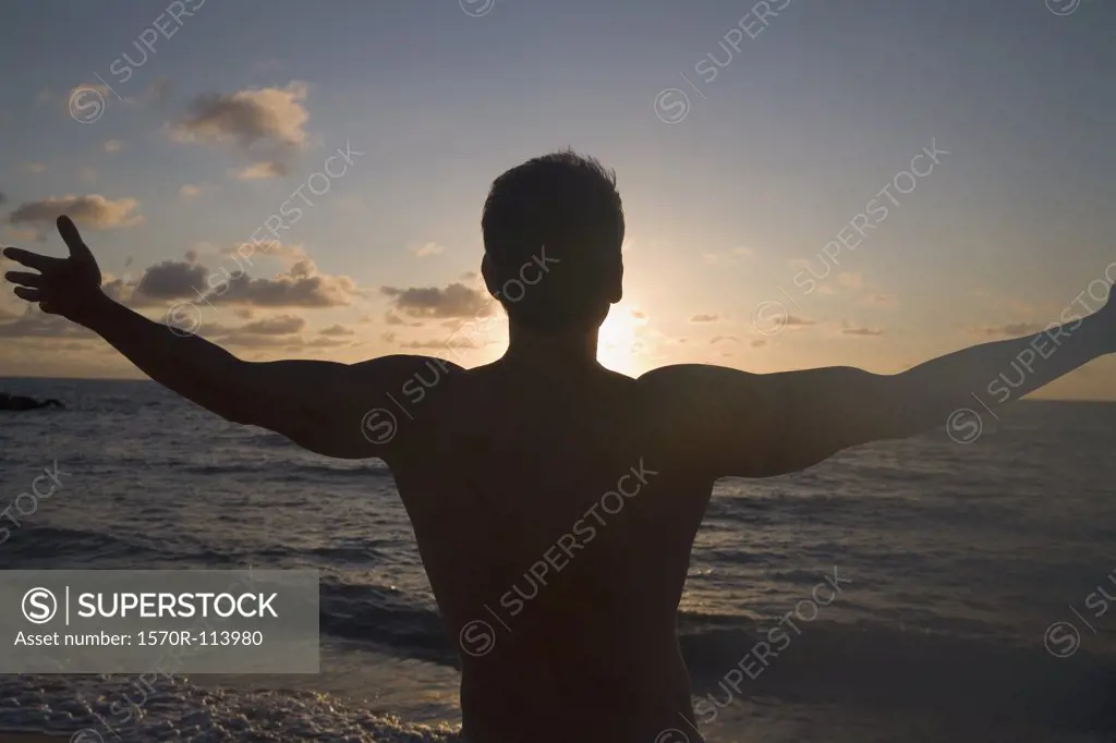 Silhouette of man in front of sunset with arms outstretched