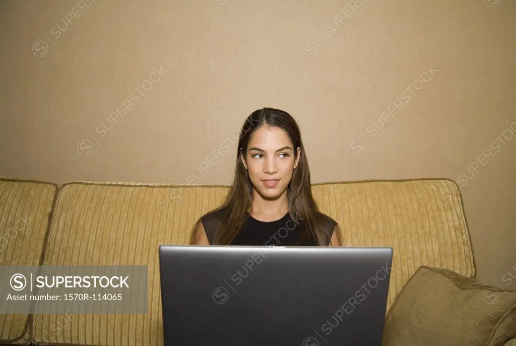 Young woman using laptop and sitting on sofa