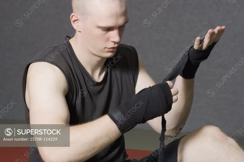 Male boxer wrapping strap around hand