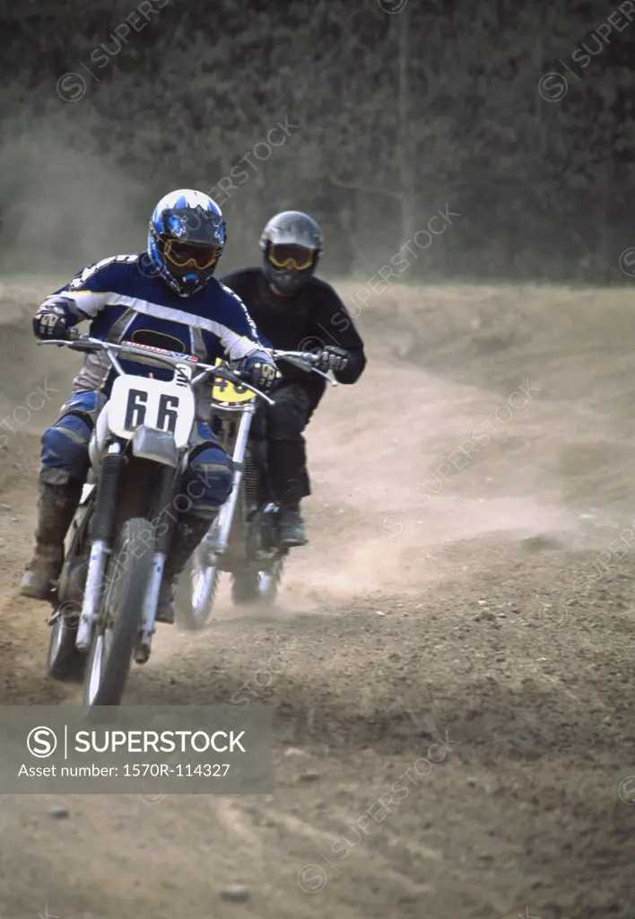 Two people racing motorcycles on dirt track