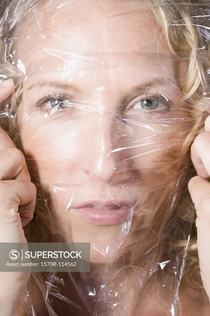 Woman stretching transparent sheet across her face