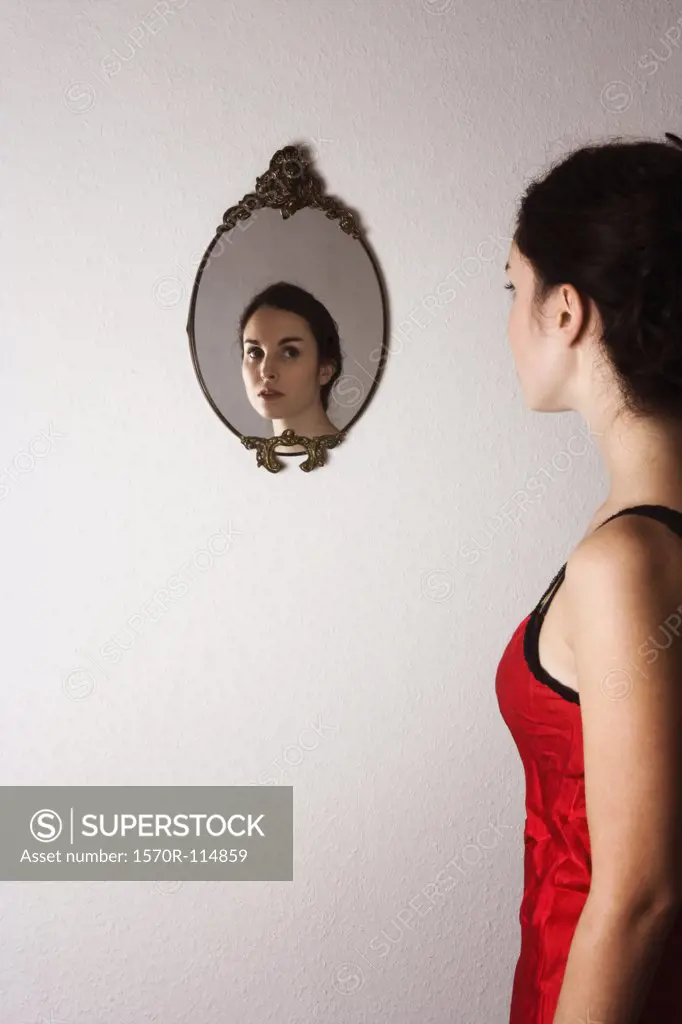 Reflection of young woman in ornate mirror on wall