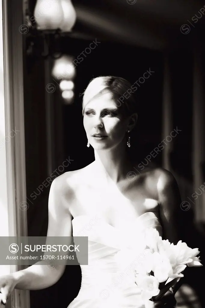 Bride holding wedding bouquet and looking out window