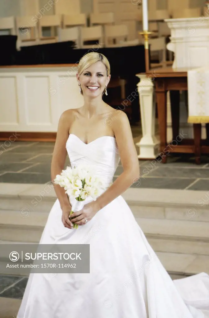 Bride holding wedding bouquet whilst standing at altar