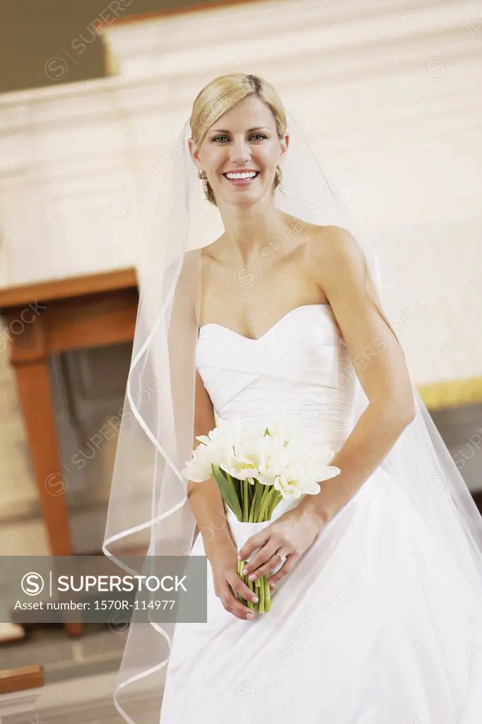 Bride holding wedding bouquet whilst standing at altar