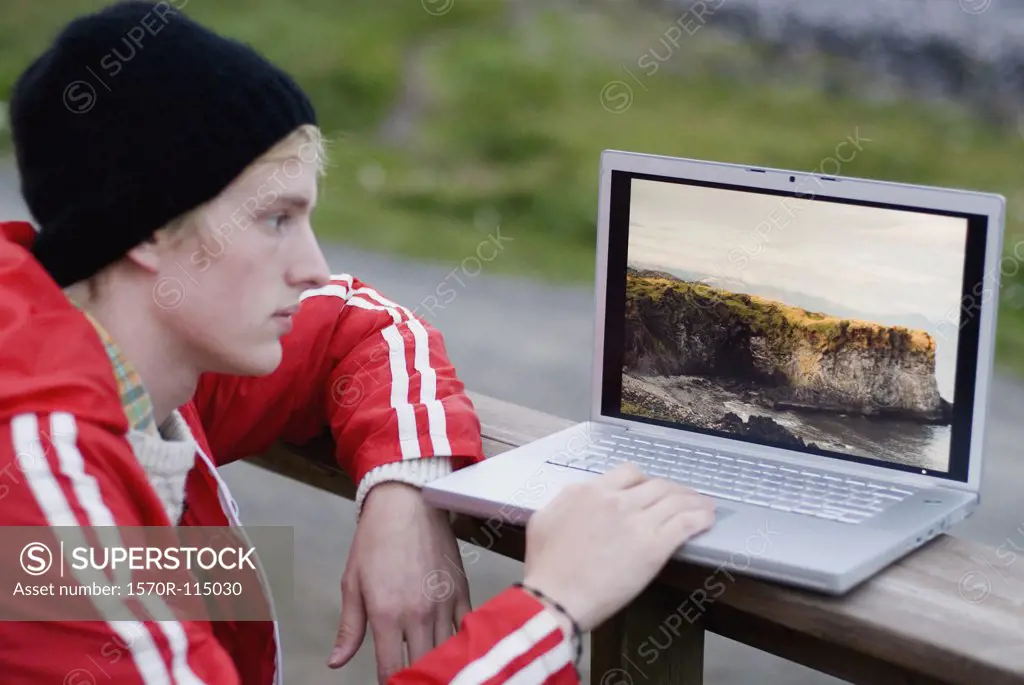 Young man using laptop outdoors