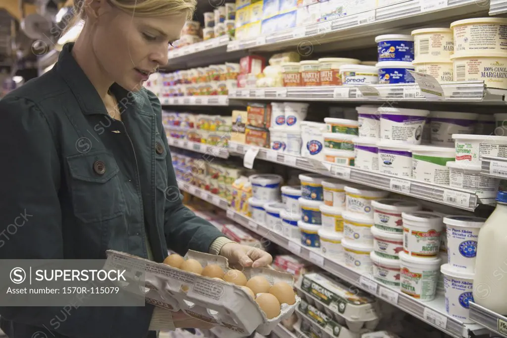 Woman in supermarket examining eggs