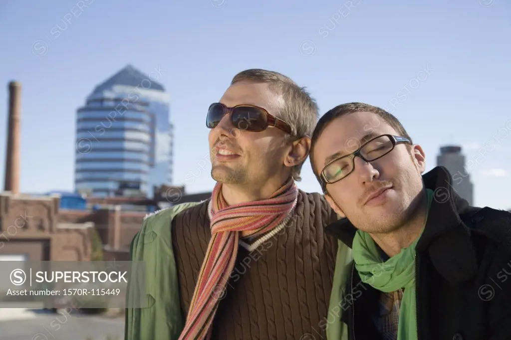 Two gay men smiling with cityscape behind
