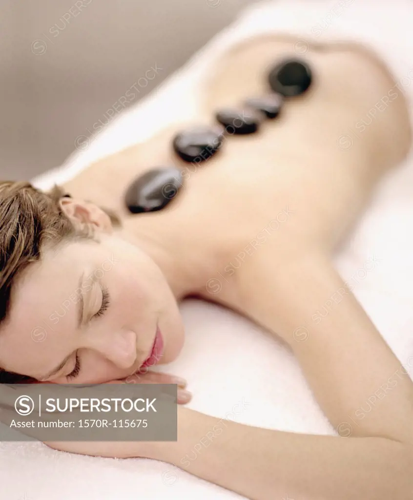 Woman lying down with therapeutic stones on her back