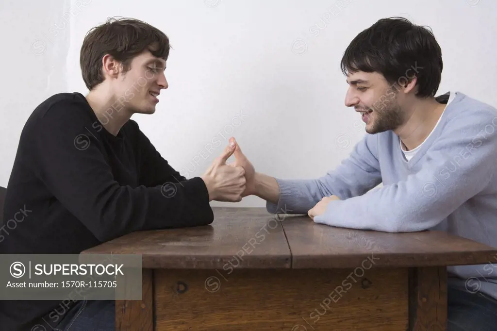 Two young men playing game and laughing at table