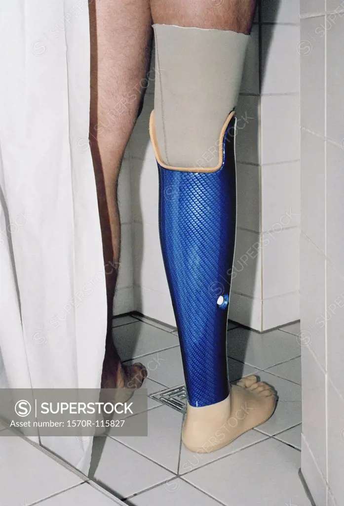 Low section of man standing in shower with prosthetic leg