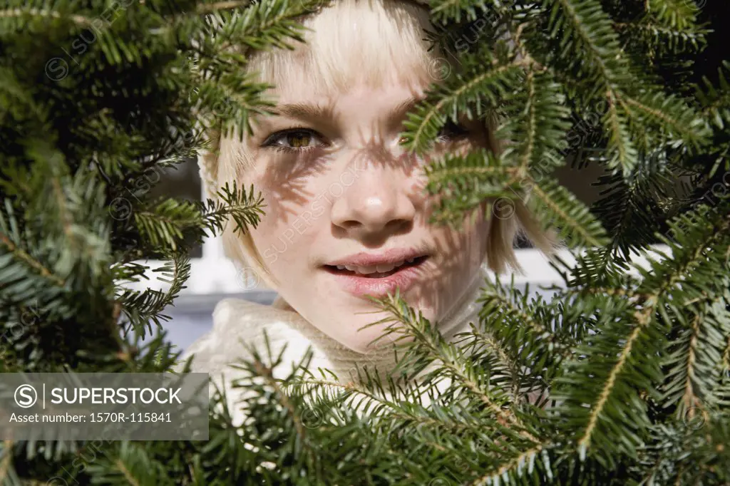 Young woman looking through a Christmas wreath