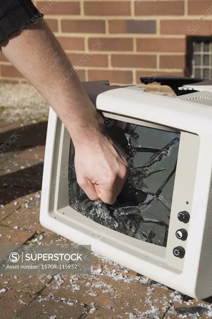 Man holding his fist to a smashed television