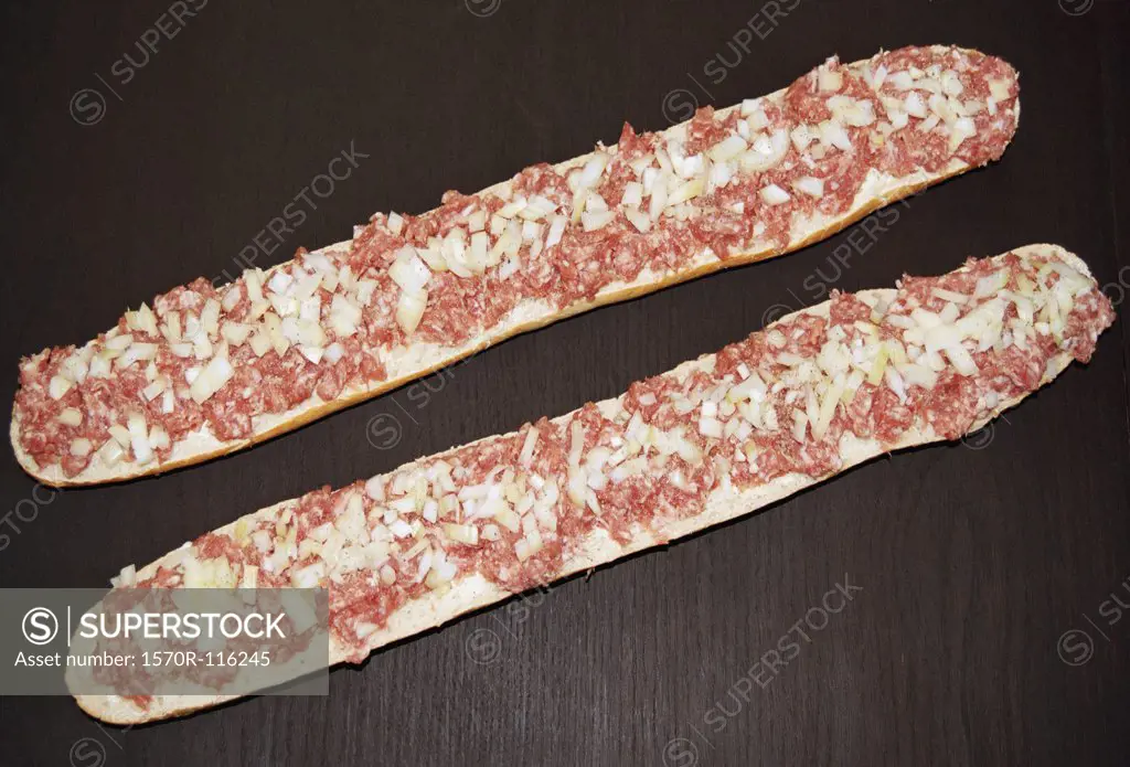 Two baguette halves with onion and meat