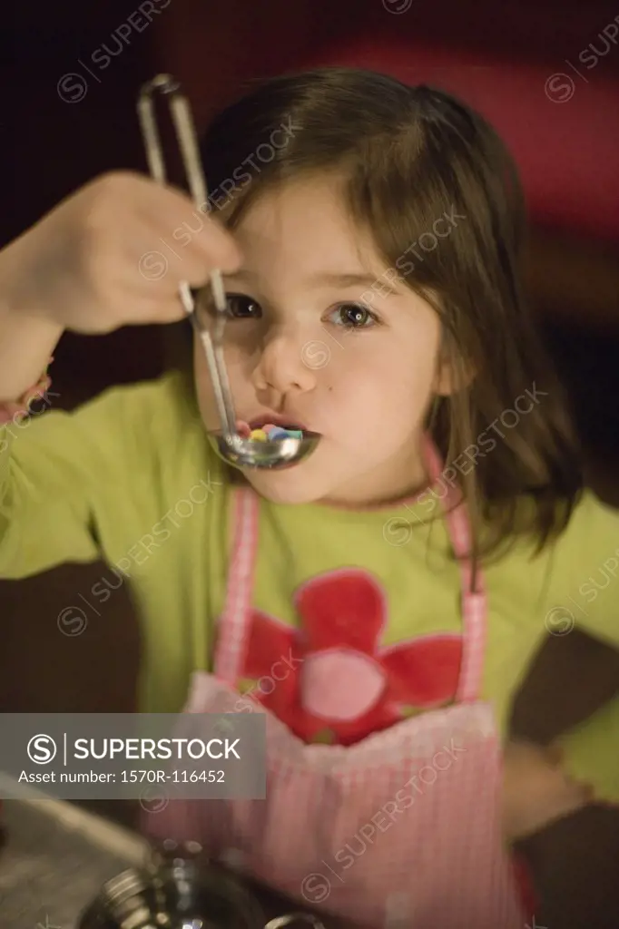 Young girl playing with a toy soup ladle