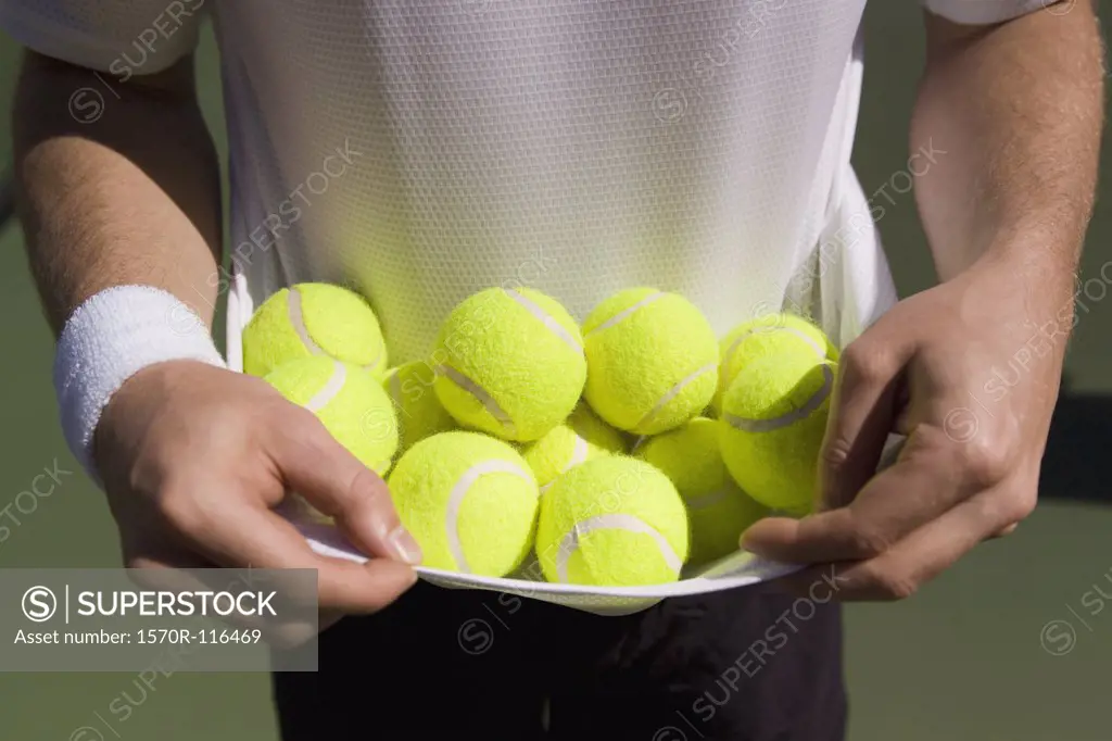 Midsection view of a man carrying tennis balls in his t-shirt