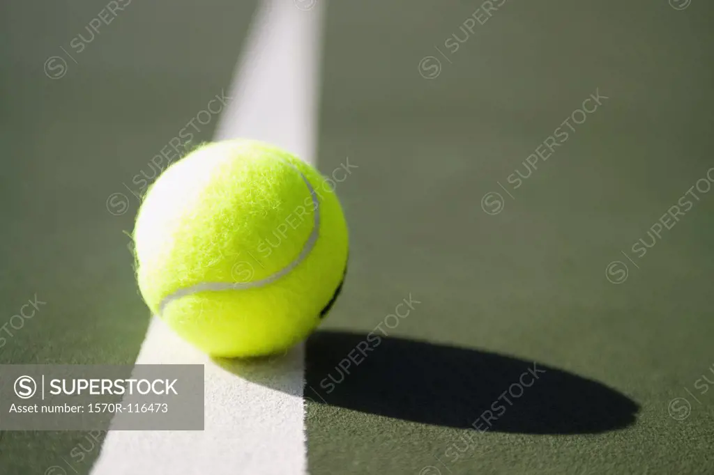 A tennis ball sitting on a white line