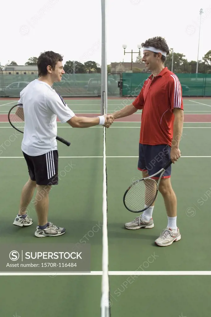 Two tennis players shaking hands across the net