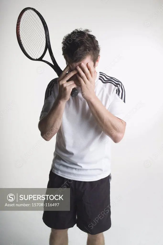 A tennis player covering his face with his hands