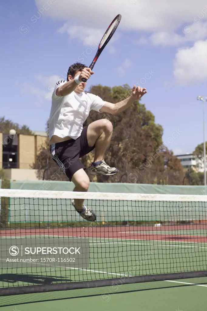 A tennis player leaping over a tennis net