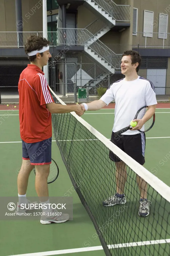 Two tennis players shaking hands across the net